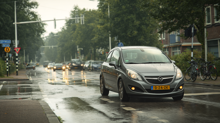 Auto rijdt door regenachtig stadsverkeer om rijervaring op te doen.